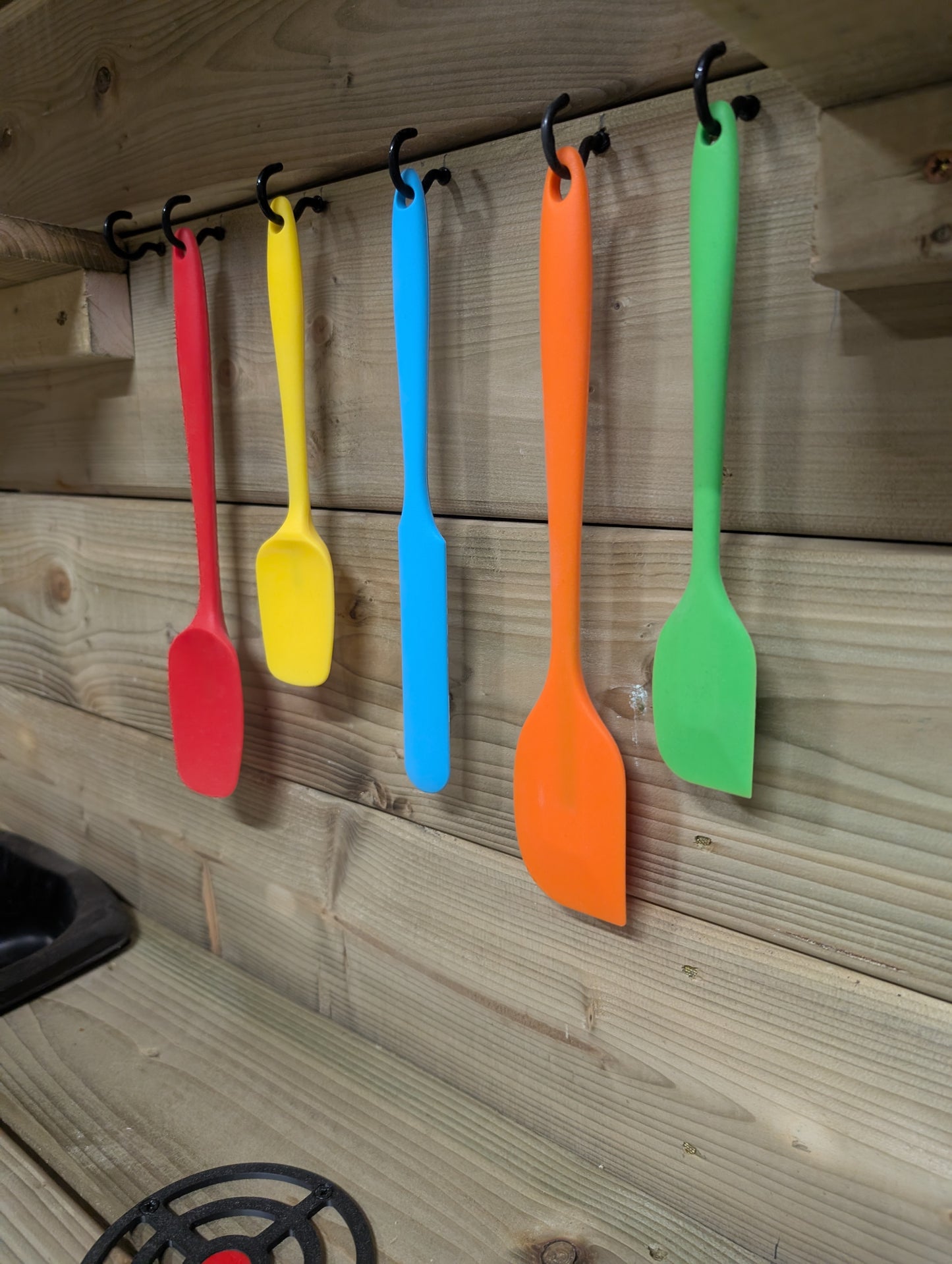 Colorful spatulas hanging on a wooden wall