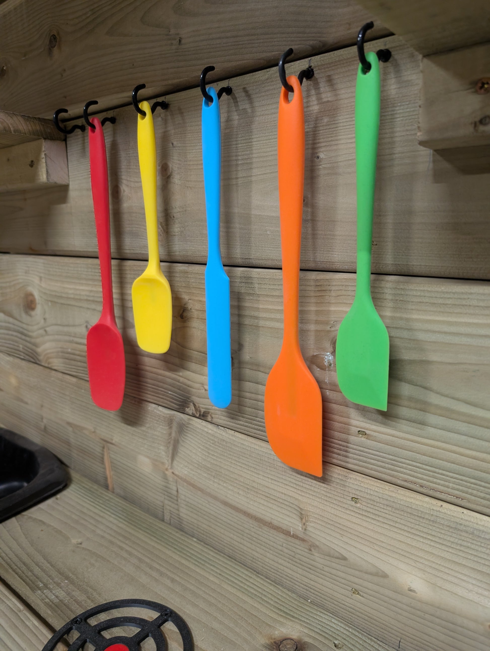Colorful spatulas hanging on a wooden wall